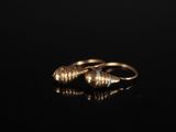 une image représentant une paire de boucles d'oreilles en or posées sur une surface noire