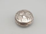 un petit bouton en argent orné d'un motif floral