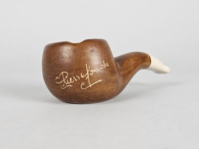une vieille pipe sur laquelle sont inscrits des mots, posée sur une table