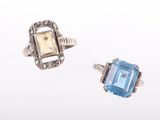 two rings with blue stones and diamonds on a white surface
