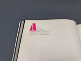 an open book with a pink and white logo on it