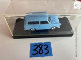 une petite voiture bleue dans une boîte transparente posée sur une table