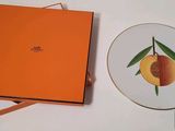 une boîte orange avec une assiette, et une assiette sur laquelle se trouve une pêche