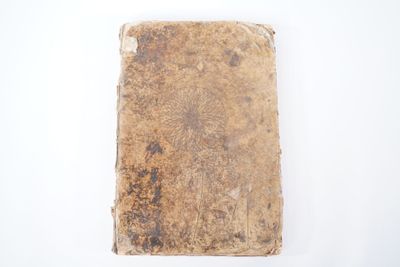 un vieux livre posé sur une surface blanche, sur fond blanc