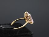 a close up of a gold ring with a pink stone in it
