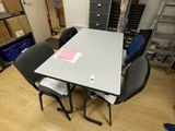 a table and chairs in a room with many boxes on the floor