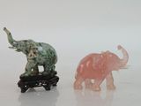 two small figurines of elephants on a white surface