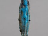 une statue égyptienne antique en pierre bleue représentant une femme, posée sur un socle noir