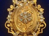 an image of a gold and diamond broochle on a blue cloth