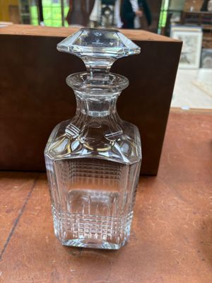 une bouteille en verre posée sur une table, avec une boîte en bois en arrière-plan