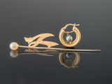 a gold earring with a pearl and a leaf on it