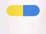 a blue and yellow pill sitting on top of a white surface