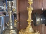 a glass display case with a gold candle and a black vase on it