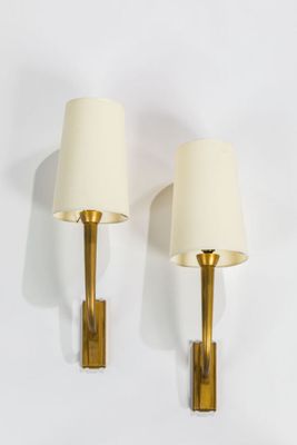 pair of brass sconces with white lamps on a white background