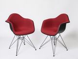 une paire de chaises Eames rouges et noires avec des pieds chromés