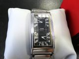 une montre argentée et noire posée sur une serviette blanche, sur une table noire
