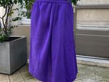 une jupe violette posée sur un mannequin devant une plante en pot