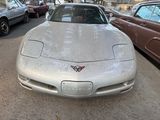 a white corvette car parked in a lot with other cars in the background