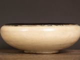 a white bowl with a black rim on a wooden table