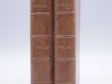 two brown books sitting on top of each other on a white surface