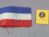 un drapeau rouge, blanc et bleu et un insigne à côté d'une feuille de papier jaune