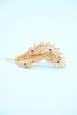 a close up of a gold brooch with pink stones on it