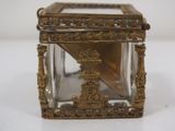 a small glass box with a gold decoration on it