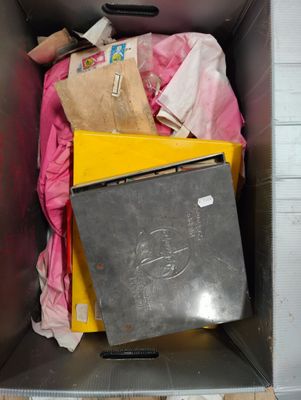 une boîte en métal posée par terre et remplie d'objets divers