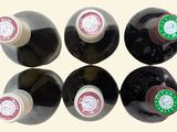 six bottles of wine are lined up in a row on a white surface