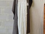 a white dress hanging on a clothes rack next to a brick wall