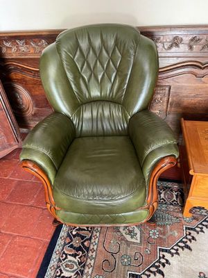 a green leather chair in a living room with a rug