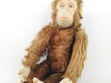 un singe en peluche assis sur une surface blanche