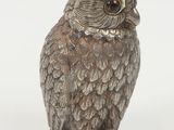 silver owl figurine sitting on a white surface with a white background
