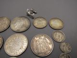 some silver coins are arranged on a table with a small silver object
