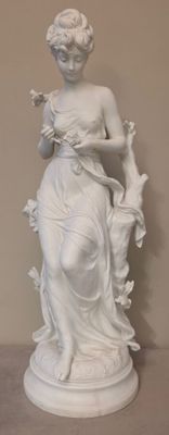 une statue représentant une femme tenant un oiseau, posée sur un socle