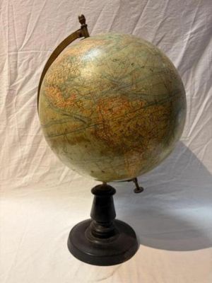 un vieux globe terrestre posé sur un socle, devant un fond blanc