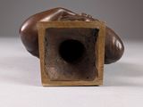 a bronze sculpture of a hand resting on a wooden block