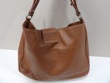 brown leather handbag sitting on a white table with a white wall in the background