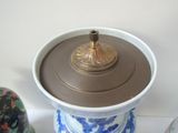 a blue and white vase with a gold lid on a table