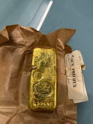 someone is holding a gold bar in their hand on a piece of paper