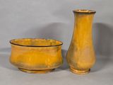 pair of yellow vases sitting next to each other on a gray surface