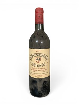 une vieille bouteille de vin posée sur une surface blanche