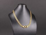un collier à chaîne en or sur un mannequin, sur fond noir