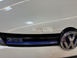 the front end of a white vw volkswagen car with a sticker on it ' s hood