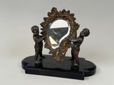 une statue représentant deux enfants, avec un miroir posé sur une table