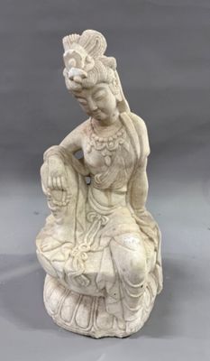 a white statue of a woman sitting on a rock with a flower in her hair