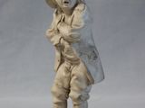 a small statue of a man with a hat and a bag
