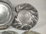 three silver plates sitting on a table with a white background