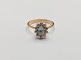 a gold ring with a blue topaz stone surrounded by small white diamonds