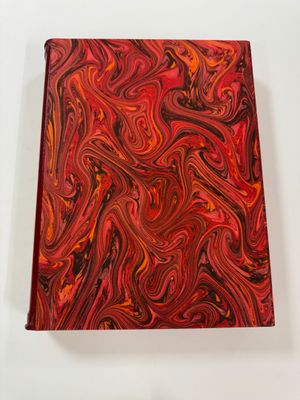 a red and black marbled notebook on a white surface